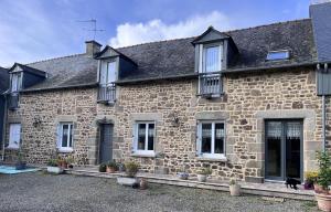 an old stone house with white windows and plants at La demeure romantique in Bazouges-sous-Hédé