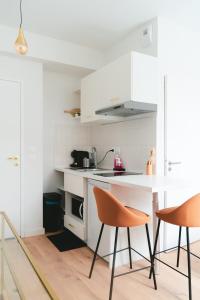 een keuken met witte kasten en een tafel en stoelen bij ô Quai St Pierre in Toulouse