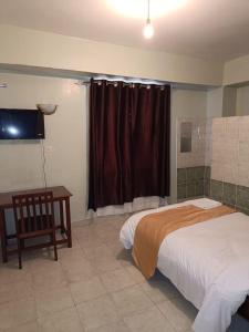 a bedroom with a bed and a desk and a television at Sislink Suites in Nairobi