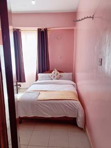 a bedroom with a bed in a pink room at Sislink Suites in Nairobi