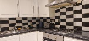 a kitchen with black and white tiles on the wall at Central Reading 2 Wash Rooms FREE PARKING in Reading