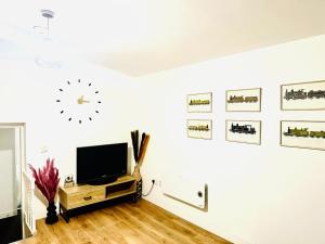 a living room with a tv and a clock on the wall at Albert Inn Apartments in Manchester