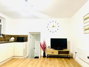 a living room with a television and a clock on the wall at Albert Inn Apartments in Manchester
