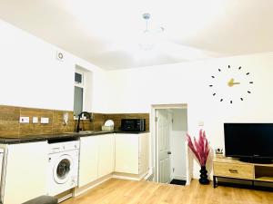 a kitchen with white cabinets and a clock on the wall at Albert Inn Apartments in Manchester