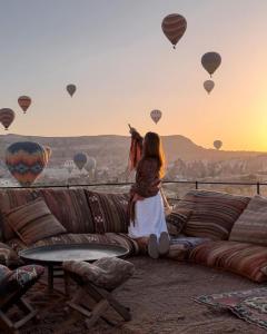 uma mulher sentada num sofá a ver balões de ar quente em Perla Cappadocia em Goreme