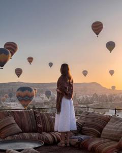 a girl standing on a couch looking at hot air balloons at Perla Cappadocia in Goreme