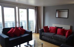 una sala de estar con 2 sofás negros y almohadas rojas en Access Apartments City, en Londres