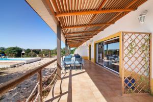 un patio con mesa y sillas bajo una pérgola en Quinta Tapada dos Machados, en Alvor