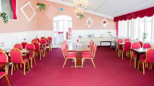 una sala da pranzo con sedie rosse e tavoli in legno di A Hotels Roskilde a Hedehusene