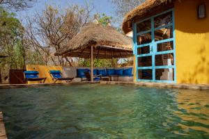 a swimming pool with chairs and a thatch umbrella at Le Campement in Bamako