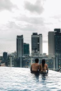 a man and woman sitting in the infinity pool of a building at Cinnamon Red Colombo in Colombo