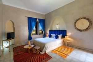 a bedroom with a large bed with blue curtains at Atlas Widan in Marrakech