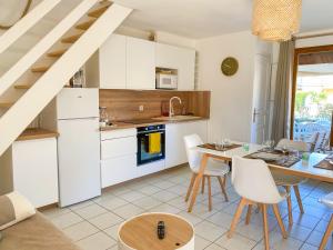 uma cozinha com armários brancos e uma mesa e cadeiras em Maison "Douceurs d'Été" em Vias