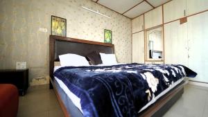 um quarto com uma cama grande e um cobertor azul em Hotel Star View em Solan