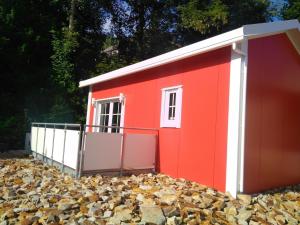 a red shed with a pile of leaves at Ferienhaus in Bad Marienberg Westerwald mit Grill und Terrasse in Bad Marienberg