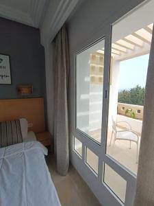 een slaapkamer met een bed en een glazen schuifdeur bij Logement S+2 dans un hôtel 4* vue mer in Bizerte