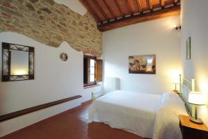 a bedroom with a white bed and a stone wall at Große Ferienwohnung in Rapale mit Terrasse, gemeinsamem Pool und Grill und Panoramablick in Rapale