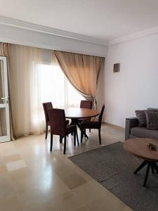 een woonkamer met een tafel en stoelen en een bank bij Logement S+2 dans un hôtel 4* vue mer in Bizerte