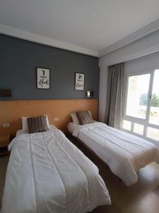 2 bedden in een slaapkamer met een raam bij Logement S+2 dans un hôtel 4* vue mer in Bizerte