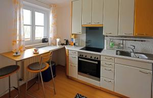 cocina con armarios blancos, fregadero y mesa en Wohnung in Großgmain mit traumhaften Bergblick, en Grossgmain