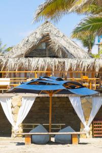 una sombrilla azul en la playa junto a un edificio en Las Cabañas de Antica, en Vichayito