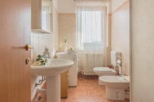 ein Bad mit 2 Waschbecken, einem WC und einem Fenster in der Unterkunft Golden View Apartment in Perledo