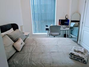 Schlafzimmer mit einem Bett und einem Schreibtisch mit einem Computer in der Unterkunft Contemporary Double Ensuite Room in Birmingham