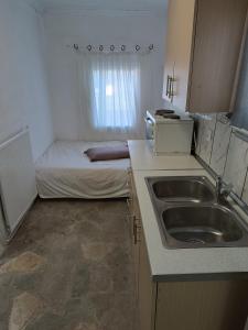 a small kitchen with a sink and a bed at Ξενώνας in Nea Kallikrateia