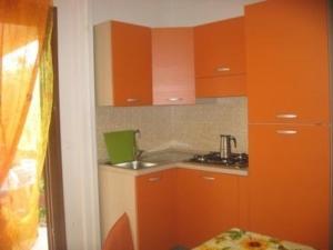 een keuken met oranje kasten en een wastafel bij Ferienhaus in kleiner Ferienanlage mit Garten, Parkplatz und Kinderschwimmbad in Peschici