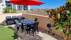 een tafel en stoelen en een rode parasol op een patio bij Appartement in Nin mit Terrasse, Garten und Grill in Nin