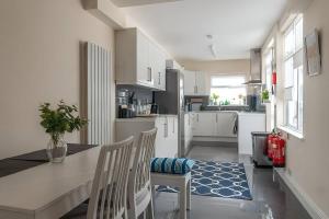 eine Küche mit weißen Schränken sowie einem Tisch und Stühlen in der Unterkunft Beautiful and spacious home in London