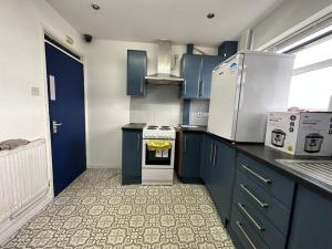 a kitchen with blue cabinets and white appliances at Cosy Retreat: Near Attractions & Comfortable! in Birmingham