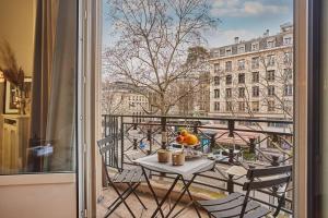 uma mesa e cadeiras numa varanda com vista para a cidade em Apartment Arc de Triomphe/ Champs Elysée by Studioprestige em Paris