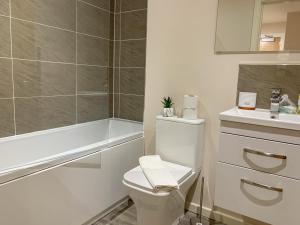 a bathroom with a toilet and a sink and a tub at Stylish Living: 1BR Apt near MCR Central in Manchester
