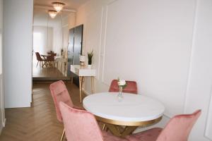 une salle à manger avec une table blanche et des chaises roses dans l'établissement Apartament No.53, à Toruń