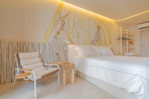 1 dormitorio con 1 cama blanca y 1 silla en Gorges Residence Salvador, en Salvador