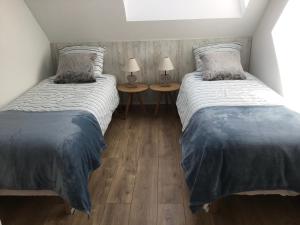 two beds in a room with two lamps on tables at Le Gîte des Fèves in Lecelles