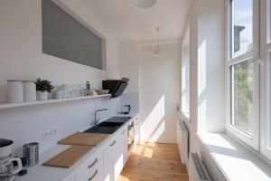une cuisine blanche avec un évier et une fenêtre dans l'établissement Das Künstlerhaus, à Niebüll