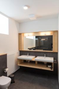 La salle de bains est pourvue de 2 lavabos et d'un miroir. dans l'établissement Das Künstlerhaus, à Niebüll