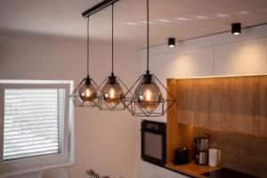 een keuken met vier lampen die aan het plafond hangen bij Bernie apartments with a pool in Zadar