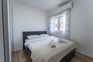 een witte slaapkamer met een bed met handdoeken erop bij Bernie apartments with a pool in Zadar +33 foto's