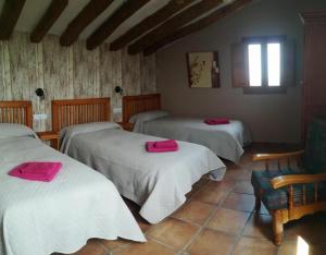 um quarto com três camas com toalhas cor-de-rosa em Santa Ana em Pedrola