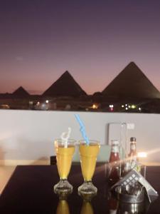 Pyramids Sun Land Veiw في القاهرة: كأسين من المشروبات على طاولة مع الأهرامات في الخلفية