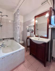 y baño con bañera, lavabo y espejo. en Appartamento in collina a 15 minuti dal mare, en Riparbella