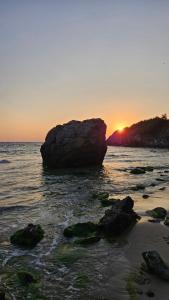 a rock in the water with the sunset in the background at Sea and Sand Apartment Greenn Life in Sozopol
