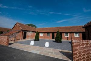 a brick building with two white benches in the courtyard at Great Blunts Stables in Billericay