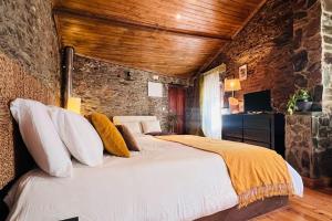 1 dormitorio con 1 cama grande en una pared de piedra en Casa da Serra - Mountain Home, en Arganil