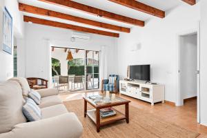 ein Wohnzimmer mit einem Sofa, einem TV und einem Tisch in der Unterkunft Casa Bruna - Binibeca Nou in Sant Lluís