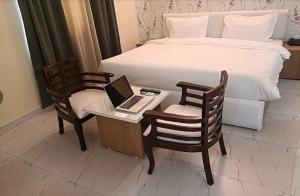um quarto com uma cama e uma secretária com um computador portátil em The Purezza Residency em Greater Noida