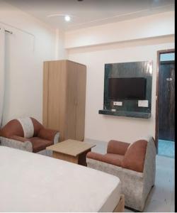 uma sala de estar com 2 sofás e uma televisão de ecrã plano em The Purezza Residency em Greater Noida